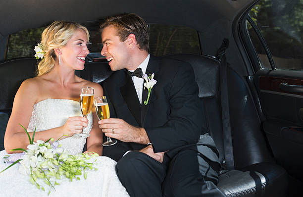 Bride and groom holding champagne glasses inside a limo.